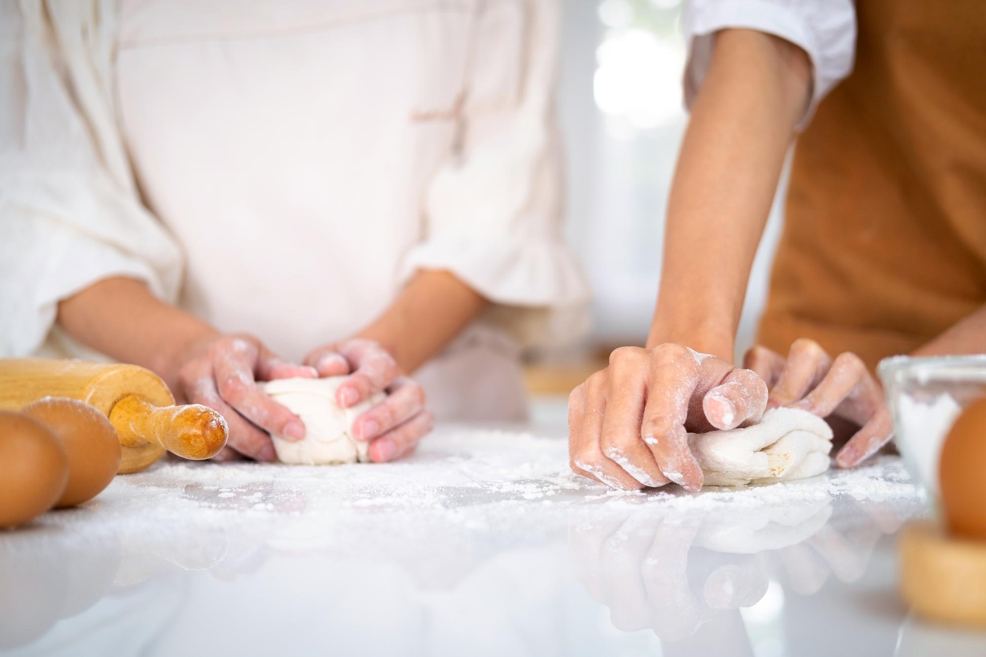 Hands kneading dough in sunlight